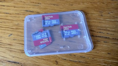 Three SanDisk Ultra 16GB microSD cards labelled refurbished in a plastic case on a wooden table